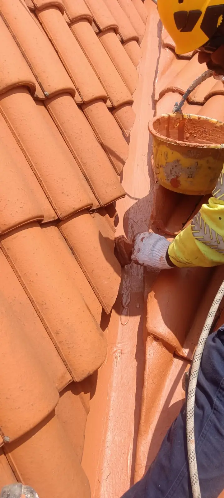 A Singapore waterproofing contractor applying waterproofing coating on tiled roof valley – highlighting the difference between professional waterproofing and surface patching